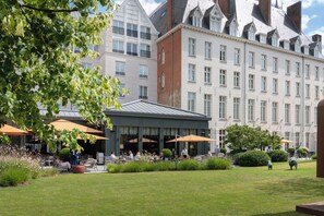 A hotel courtyard with outdoor seating, a covered area, and a well-maintained lawn. - Dukes’ Palace – by Dukes’ Hotel Collection (Bruges)