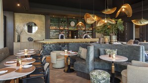 A modern bar area with seating, a bar counter, and a large mirror on the wall. - Dukes’ Palace – by Dukes’ Hotel Collection (Bruges)