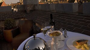 A rooftop dining setup with a statue, cityscape, and a variety of dishes. - Dukes’ Palace – by Dukes’ Hotel Collection (Bruges)