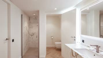 A modern bathroom with a marble vanity, a glass-enclosed shower, and a toilet.