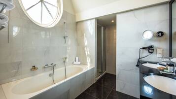 Une salle de bain moderne dotée d’une grande baignoire, d’une douche séparée et d’un meuble-lavabo avec un miroir.