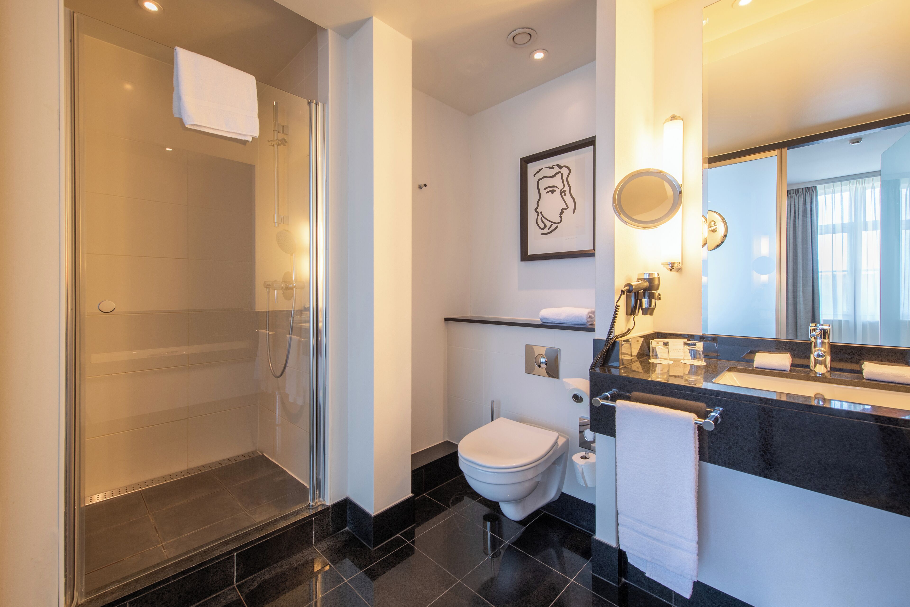 Un baño moderno con cabina de ducha de vidrio, inodoro y tocador con espejo.