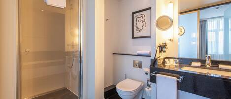 Un baño moderno con cabina de ducha de vidrio, inodoro y tocador con espejo.