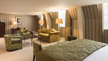 Et hotelværelse med en stor seng, to lænestole, en sofa, et lille bord og en lampe.