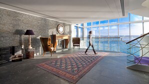 Una habitación amplia con un ventanal grande, chimenea y un tapete estampado.