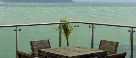 Une table et des chaises en bois sur un balcon donnant sur la mer.