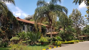 A building with a red-tiled roof, surrounded by lush greenery and various plants. - La Mada Hotel (Nairobi)