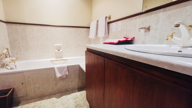 A bathroom with a bathtub, a sink, and a mirror. - La Mada Hotel (Nairobi)