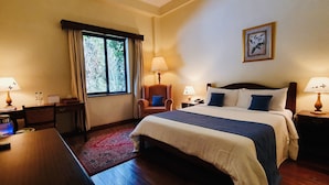 A hotel room with a bed, two bedside tables with lamps, a desk with a chair, a TV, and a window with curtains. - La Mada Hotel (Nairobi)
