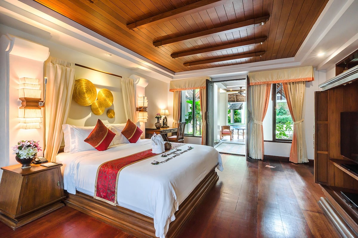 A spacious hotel room with a large bed, wooden flooring, and a television.