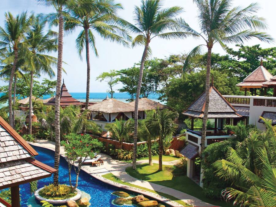 Un resort con piscina, palmeras y vista al océano.
