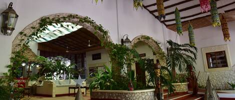 An interior with a stone archway, a statue, and hanging lanterns.