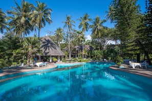 A pool surrounded by palm trees and lounge chairs. - Kilifi Bay Beach Resort (Kilifi)