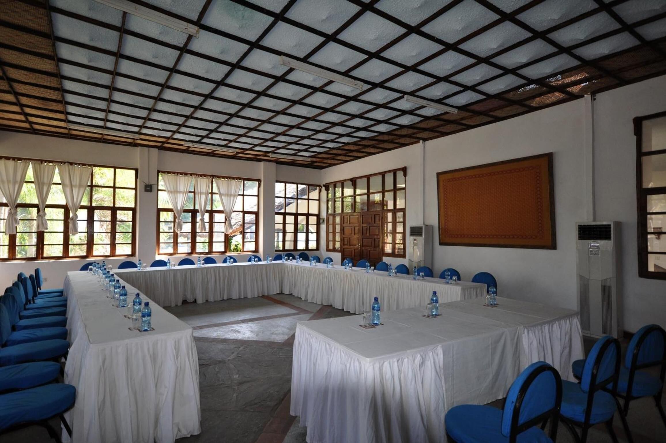 A conference room with a long table, blue chairs, and white tablecloths.
