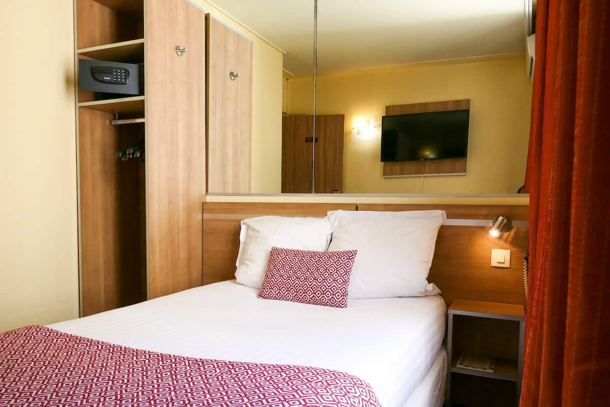 Een hotelkamer met een bed, een kledingkast, een televisie en een nachtkastje.