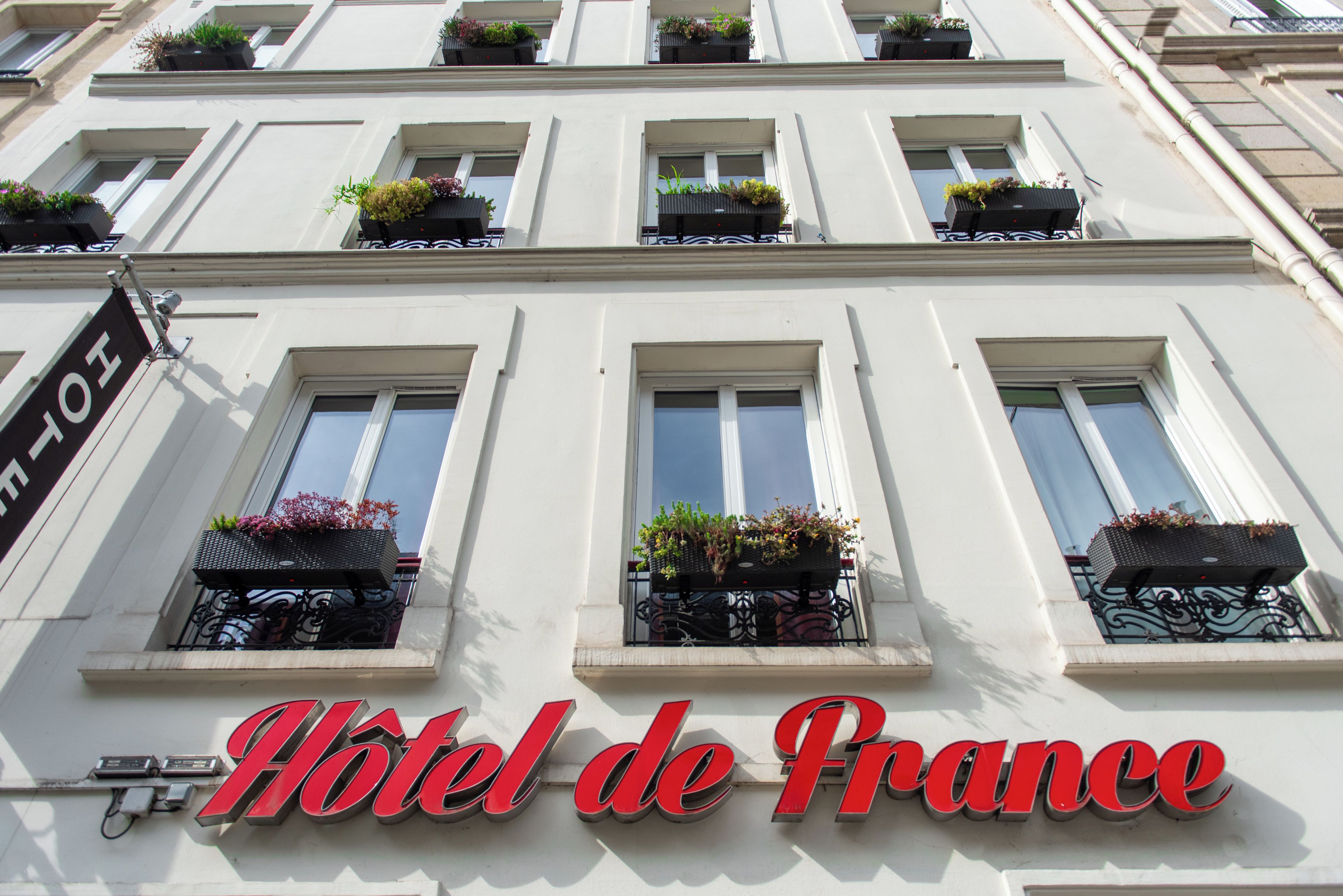 A hotel facade with multiple windows, some with flower boxes, and a prominent sign reading 'Hotel de France'.