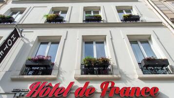 A hotel facade with multiple windows, some with flower boxes, and a prominent sign reading 'Hotel de France'.