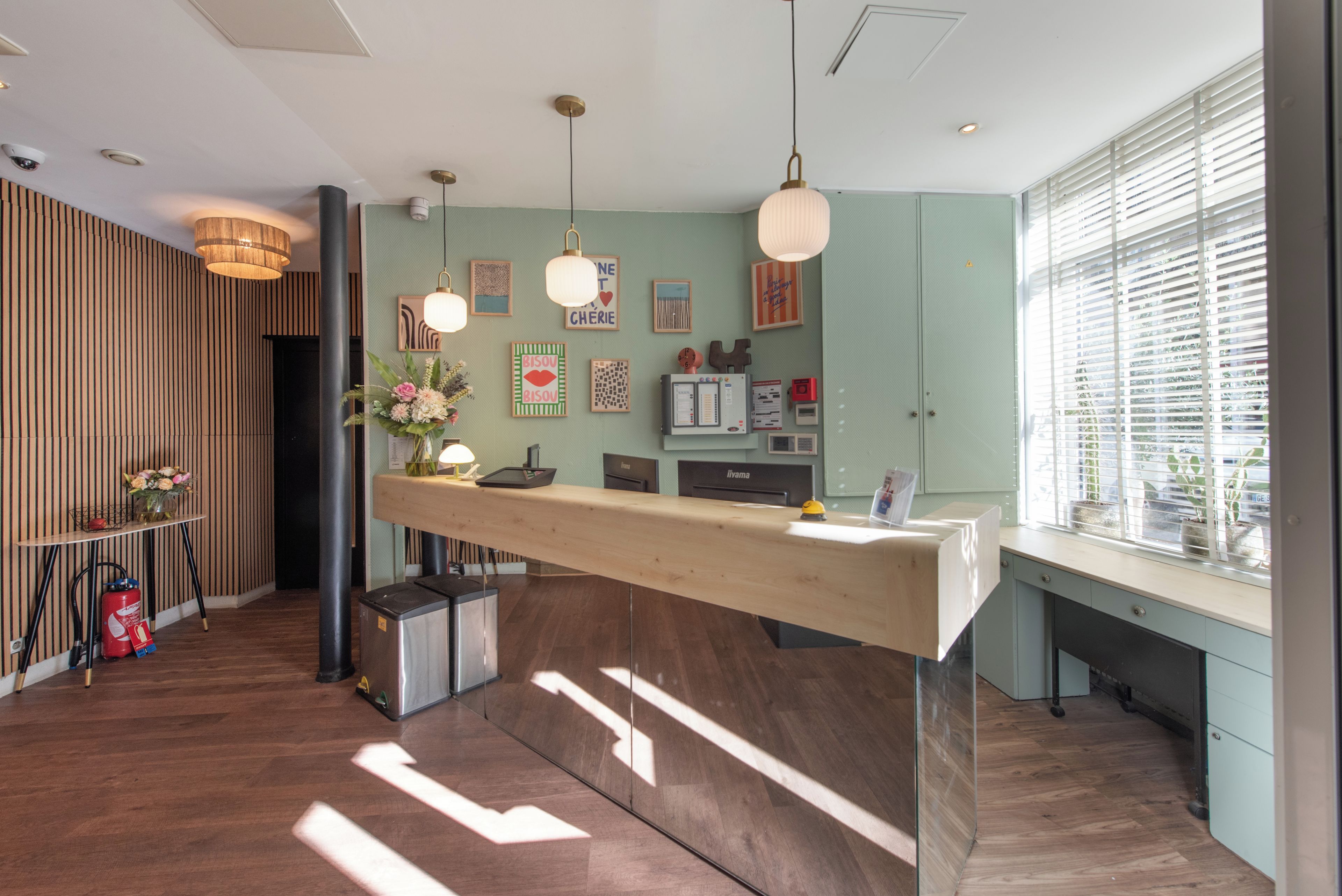 A modern reception desk with a wooden counter, pendant lighting, and a view of the city through large windows.