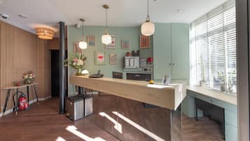 A modern reception desk with a wooden counter, pendant lighting, and a view of the city through large windows.