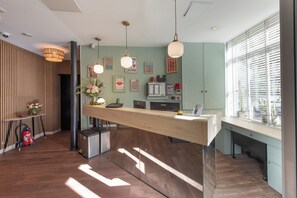 Un comptoir d’accueil moderne, doté d’un plan de travail en bois, d’un éclairage suspendu et offrant une vue sur la ville grâce à de grandes fenêtres.