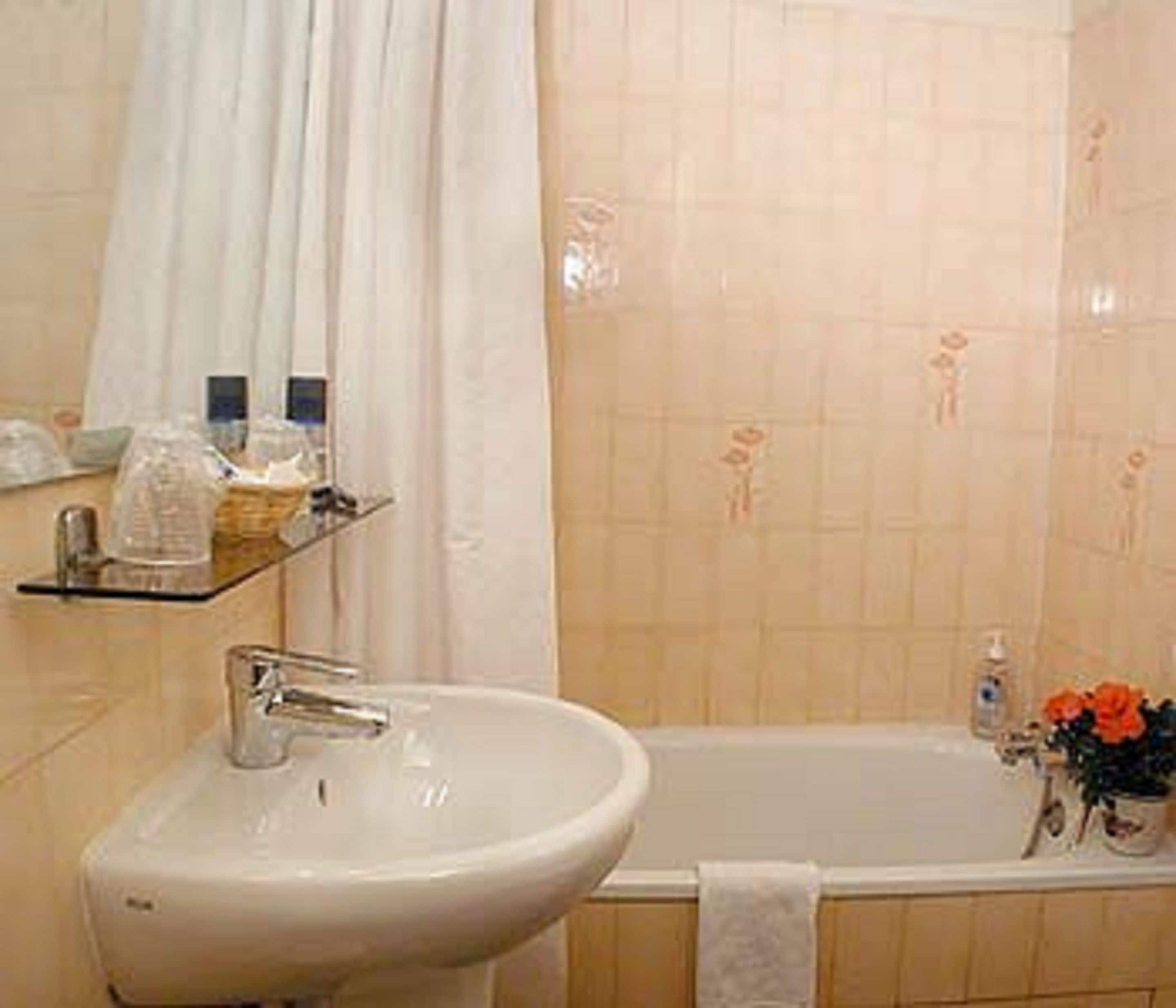 Un baño con lavamanos, espejo, cortina de ducha y bañera.