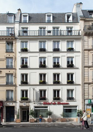 Een meerlaags hotel in klassieke Europese stijl, met balkons voorzien van metalen hekken en plantenbakken.