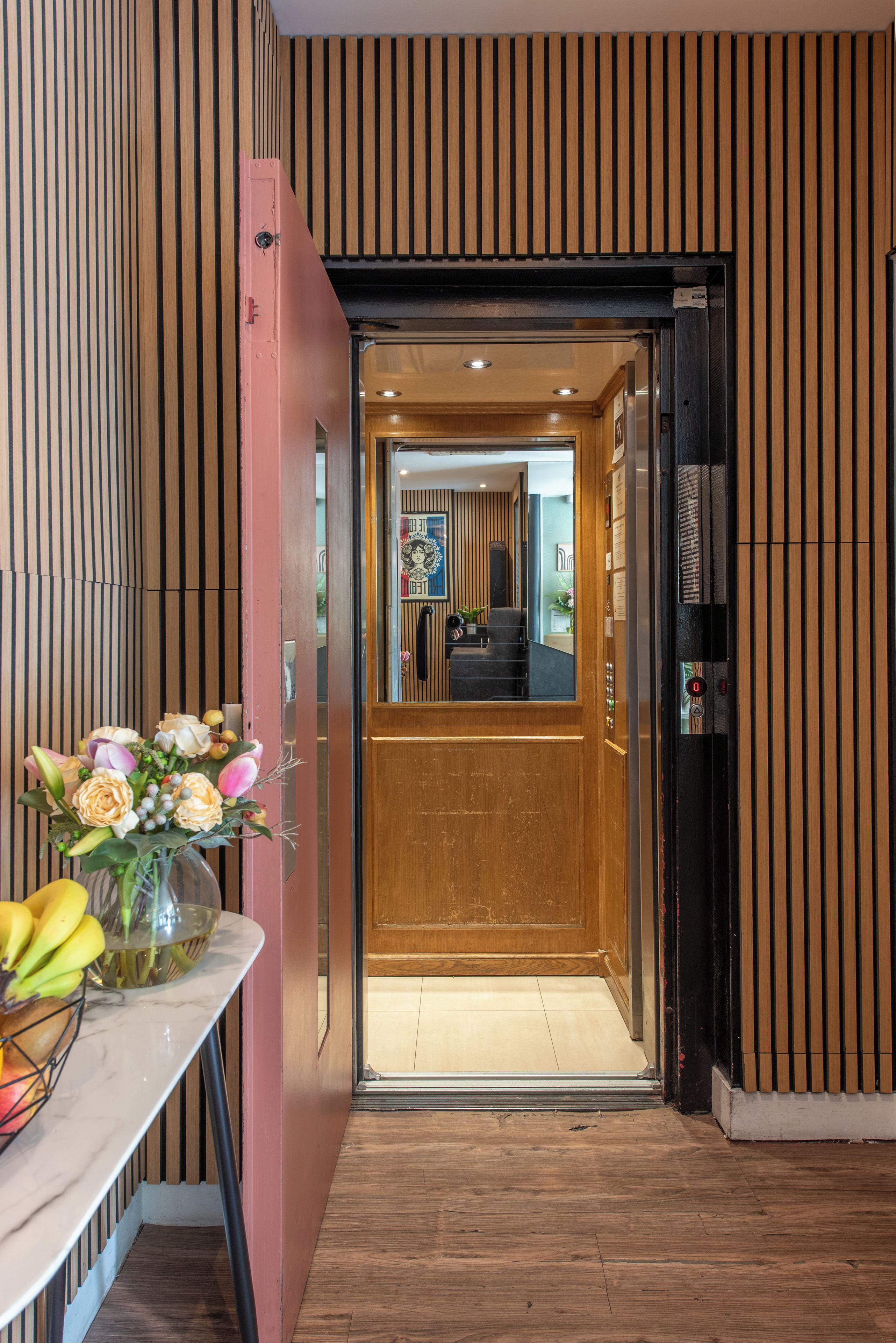 A hotel entrance with a wooden interior, a reception desk, and a glass door.