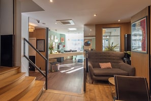 A modern interior with a staircase leading to a living area, a sofa, and a dining table. - Hotel de France Quartier Latin (Paris)