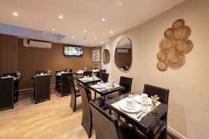 A restaurant with wooden panel walls, a TV mounted on the wall, and a decorative wall piece. - Hotel de France Quartier Latin (Paris)