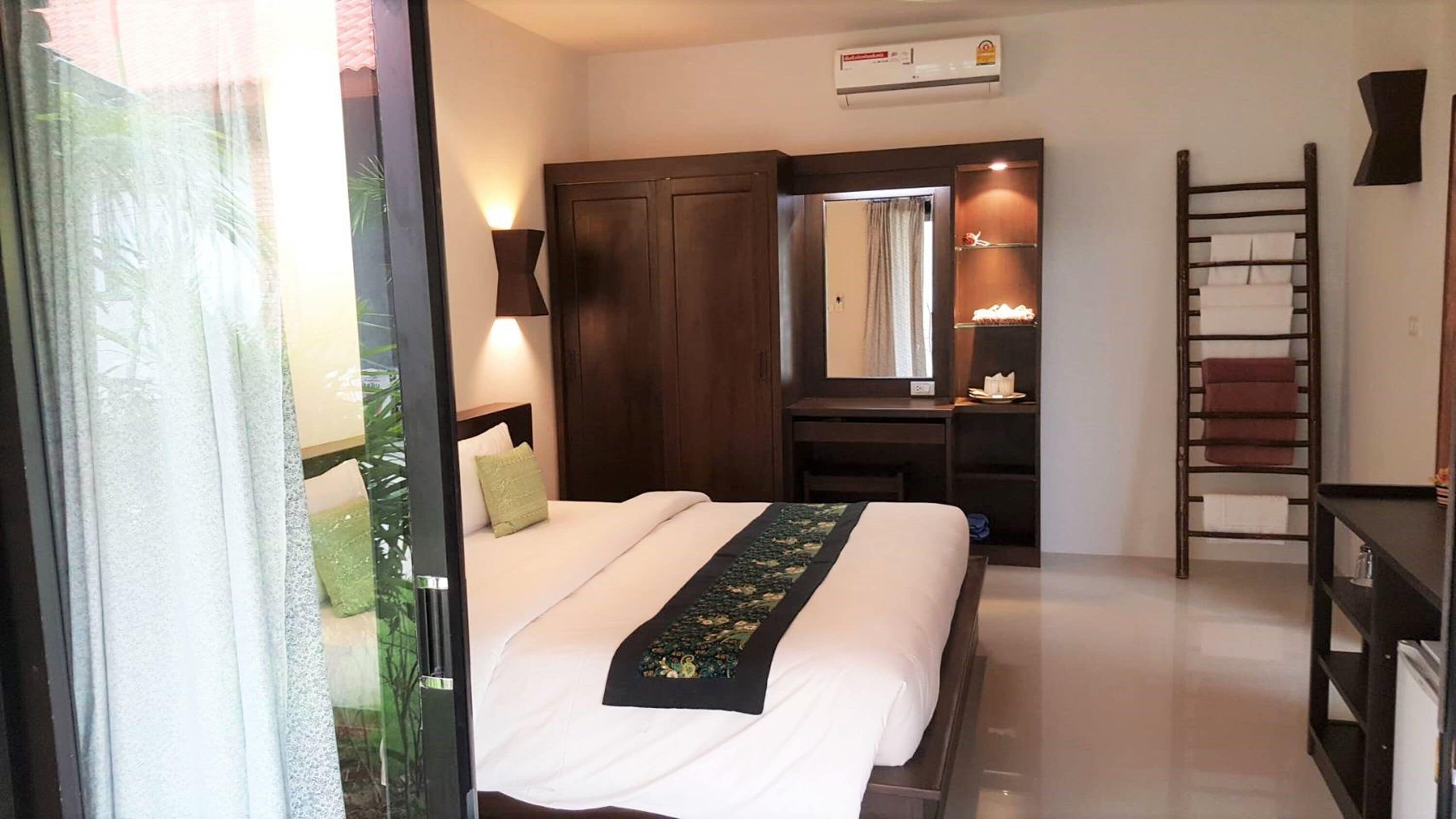 Habitación de hotel con cama, escritorio, armario, espejo y escalera.