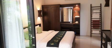 Habitación de hotel con cama, escritorio, armario, espejo y escalera.