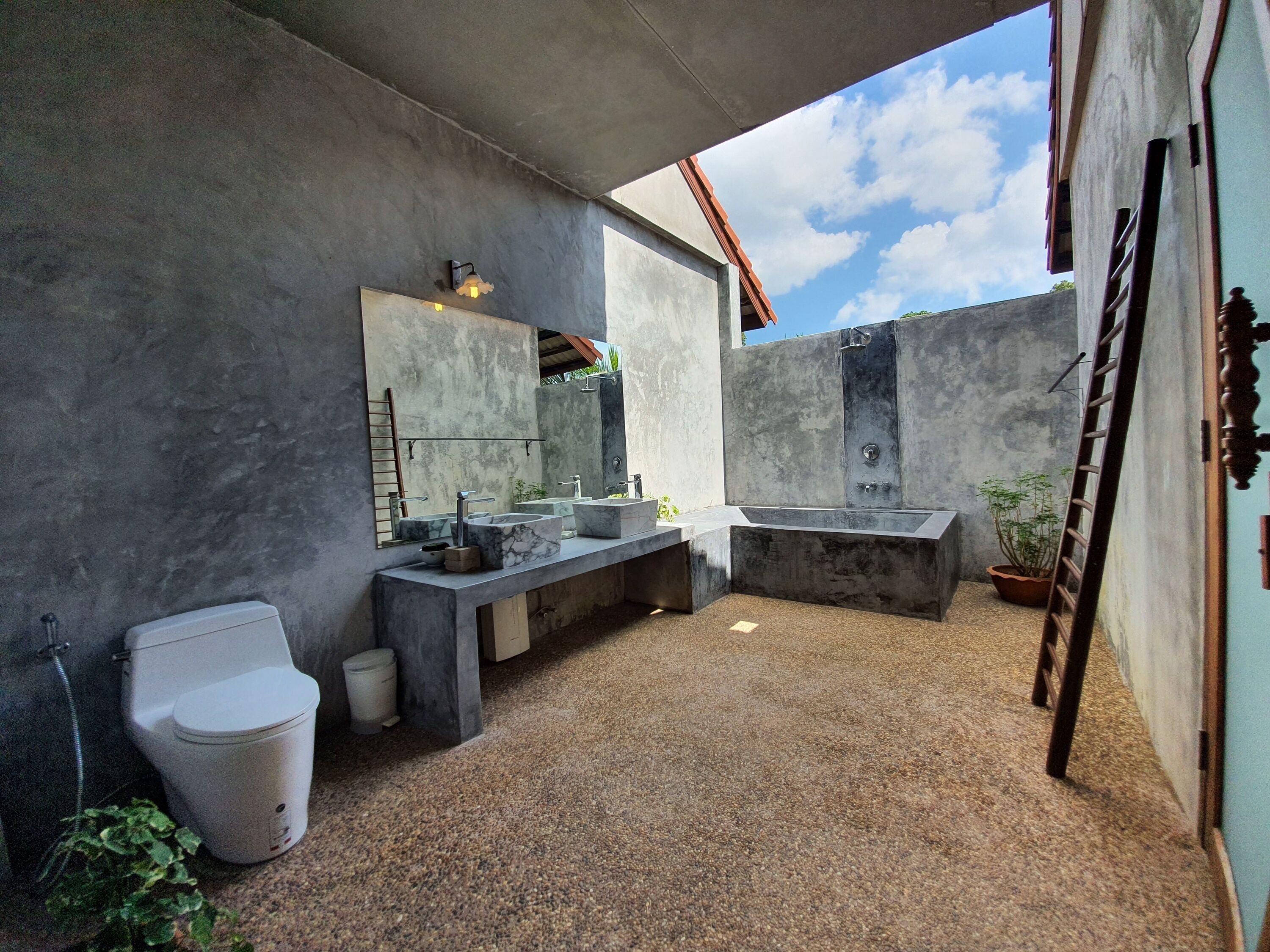 A modern bathroom with a large bathtub, a double sink, and a toilet.