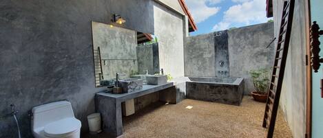 A modern bathroom with a large bathtub, a double sink, and a toilet.