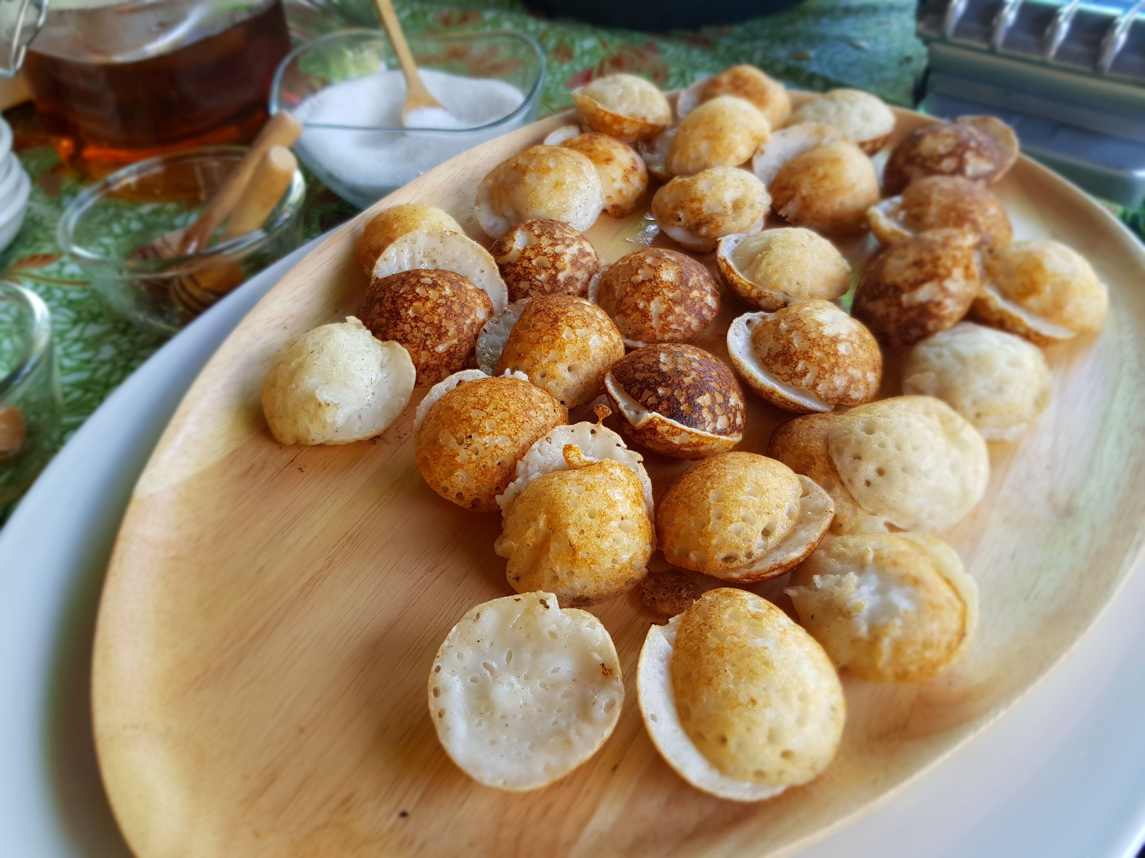 A wooden plate with various fried snacks, a glass of tea, and a bowl of white powder.