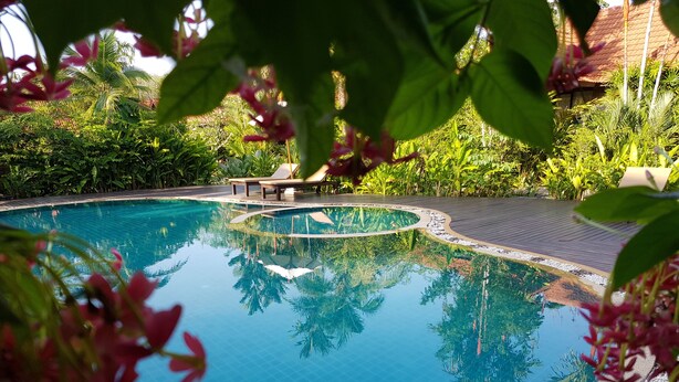 A clear blue pool surrounded by lush greenery, with a wooden deck and lounge chairs. - Tropicana Lanta Resort (Ko Lanta)