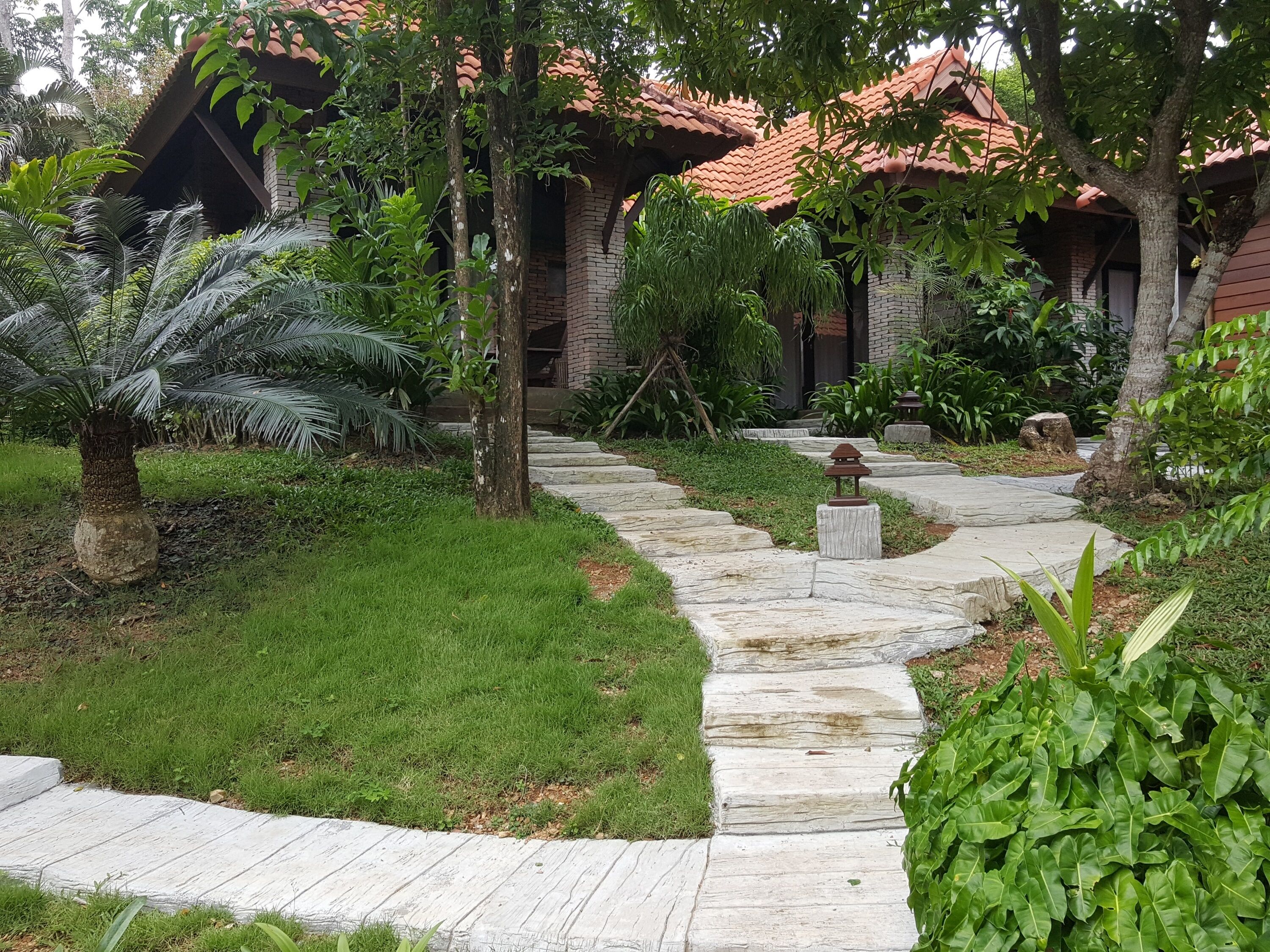 A stone pathway leading to a building with a red-tiled roof.