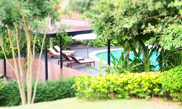 A poolside area with lounge chairs and a covered seating area.