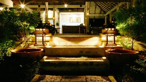 A well-lit outdoor area with steps leading to a building, surrounded by potted plants and traditional lanterns. - Tropicana Lanta Resort (Ko Lanta)