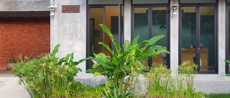 Ein Gebäude mit einer Empfangshalle, großen Fenstern und einem gepflegten Garten mit Betonpflanzgefäßen.