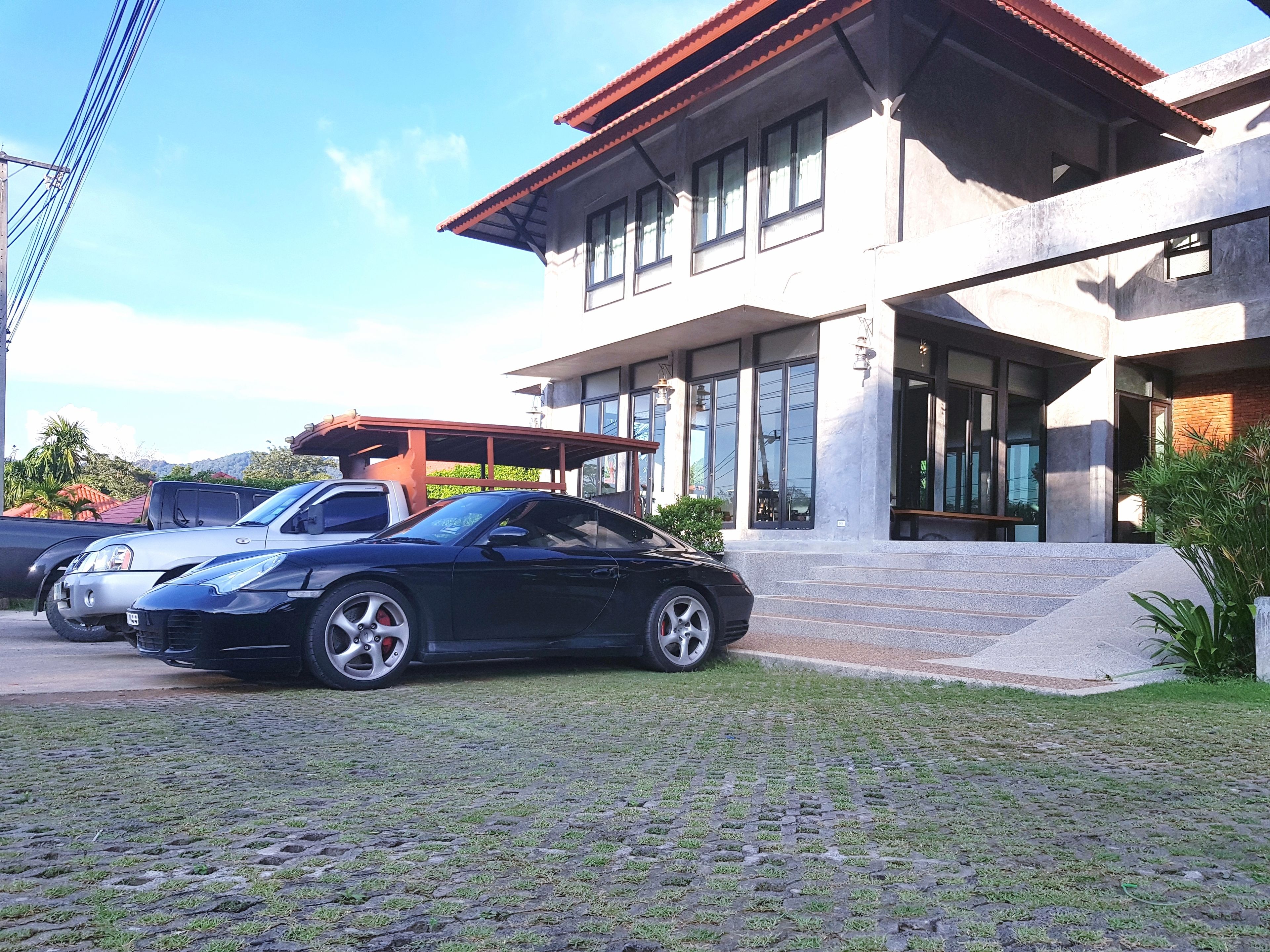 A modern building with a paved driveway and a parked black car.