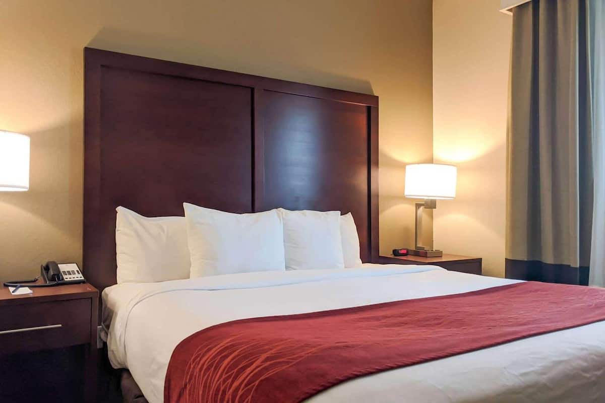 Une chambre d’hôtel avec un grand lit, deux tables de chevet, un téléphone et une lampe.