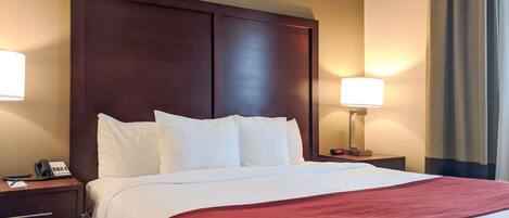 Habitación de hotel con una cama grande, dos lámparas de noche, un teléfono y una mesita de noche.