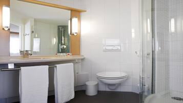 A modern bathroom with a large mirror, a toilet, a shower enclosure, and a towel rack.