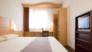 A hotel room with a bed, a desk, a television, and a wardrobe. - ibis Cotonou (Cotonou)