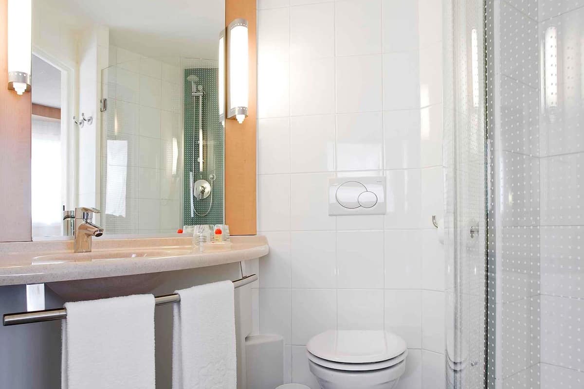 A modern bathroom with a glass shower enclosure, a white toilet, and a sink with a mirror.