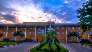 A building with a symmetrical facade, multiple windows, and a central entrance with a landscaped garden. - ibis Cotonou (Cotonou)
