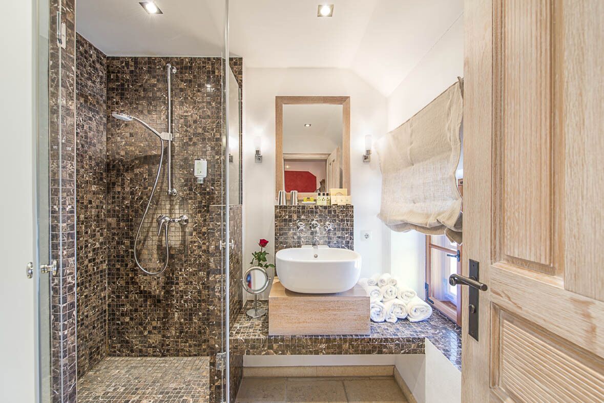 Un baño moderno con cabina de ducha de vidrio, lavabo blanco y tocador de madera.