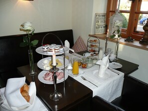 A breakfast setting with a three-tiered tray of pastries, a candle, and a sign suggesting breakfast in bed. - Romantik Hotel Chalet am Kiental (Herrsching am Ammersee)