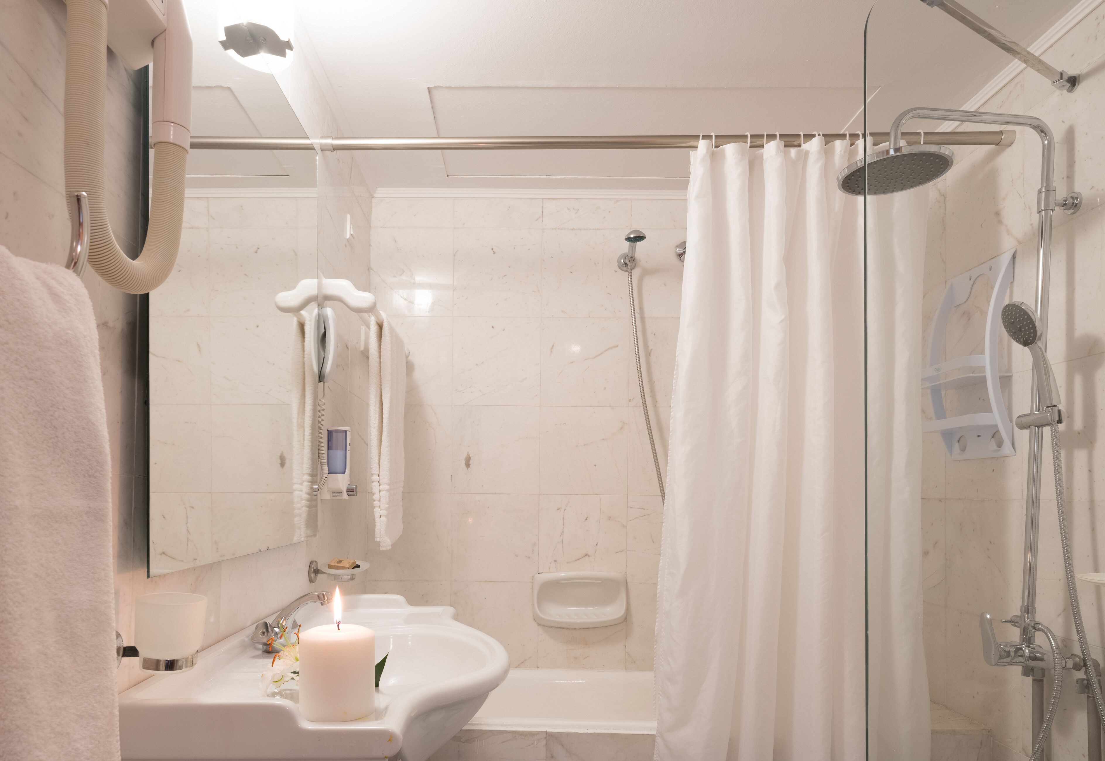 A bathroom with a sink, mirror, and shower.
