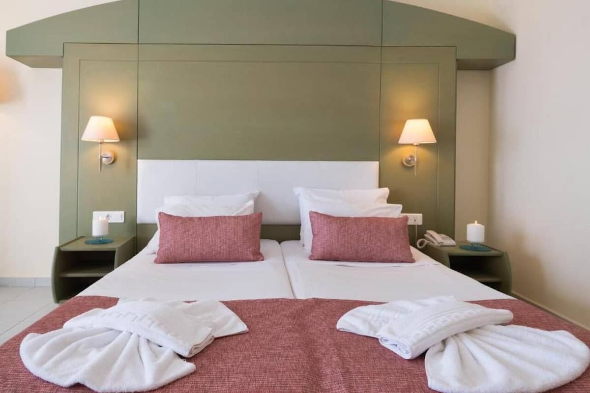 Un lit double avec deux oreillers, une table de chevet avec une lampe et une autre table de chevet avec un téléphone et une bougie.